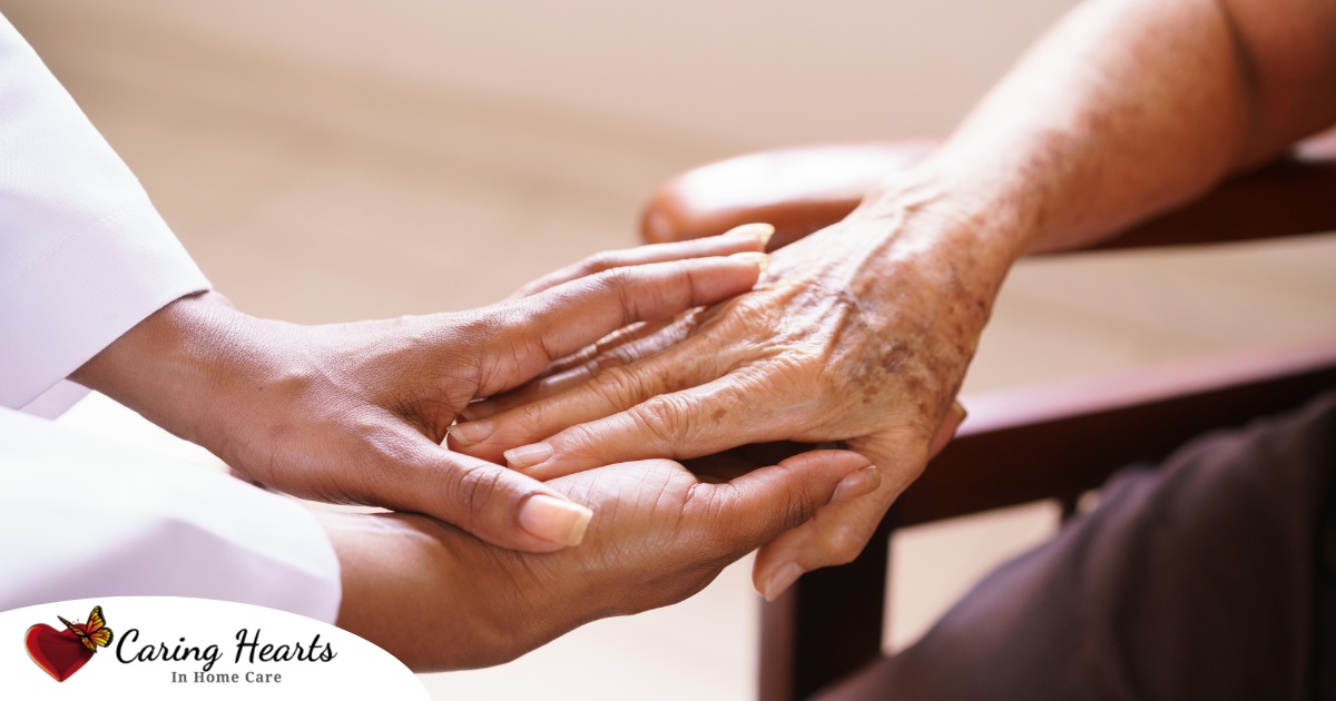 A pair of younger hands hold older ones, representing the compassionate care that a professional caregiver can provide.