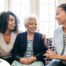 A caregiver talks with a client and her daughter, representing the type of communication that is vital when taking on a person-centered care approach.