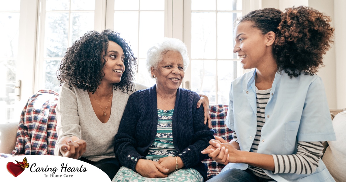 A caregiver talks with a client and her daughter, representing the type of communication that is vital when taking on a person-centered care approach.