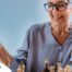 An older woman plays chess, an activity that can help older adults stay sharp.