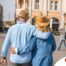 2 older adults hug while on vacation representing the successful outing that can still happen while caring for elderly loved ones.